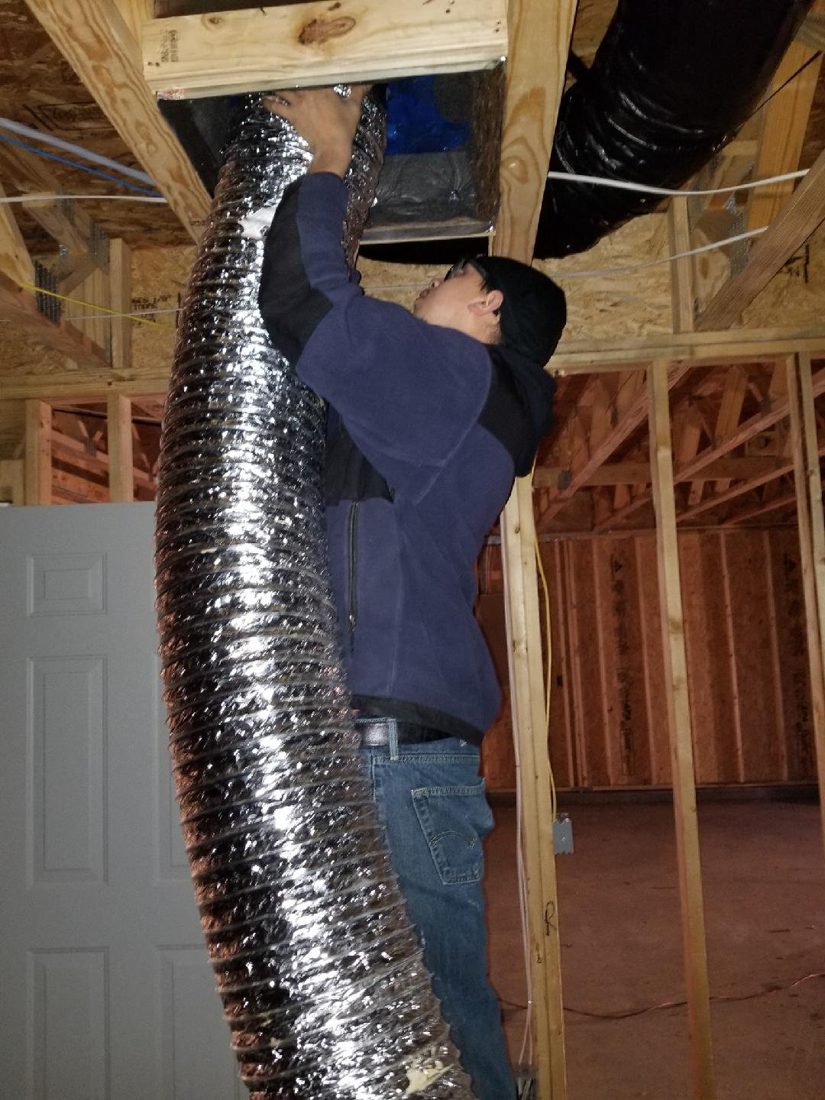 ESG technician in protective equipment sealing a duct system for leakage testing in a Greensboro home