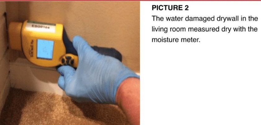 Moisture meter confirming dry conditions on a remediated wall