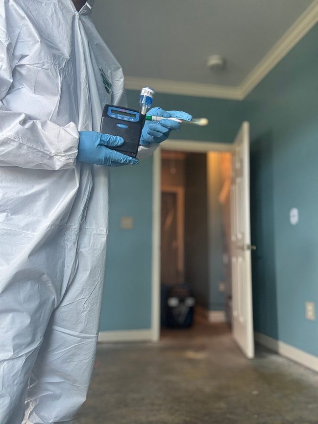 Technician in protective equipment working in a building hallway during an environmental testing project in North Carolina
