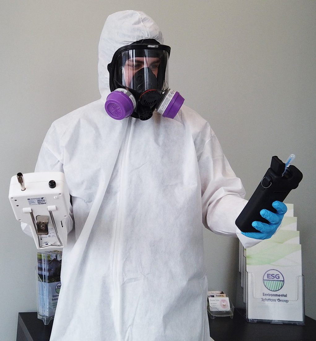 ESG technician in PPE operating an air sampling device inside containment