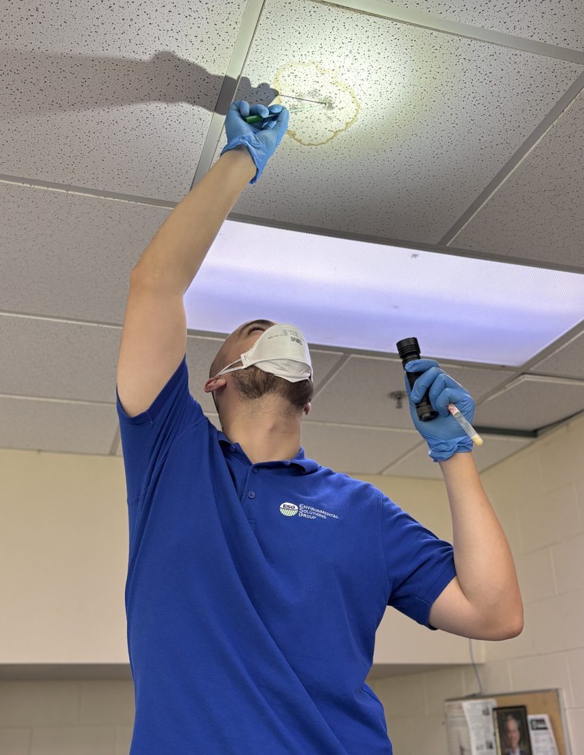 Technician installing an air quality monitor inside a school building